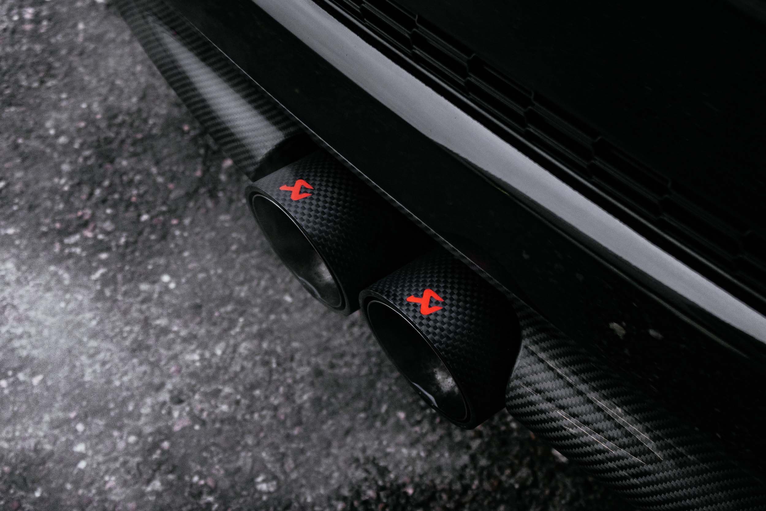 a close up of a black car with red exhaust pipes .